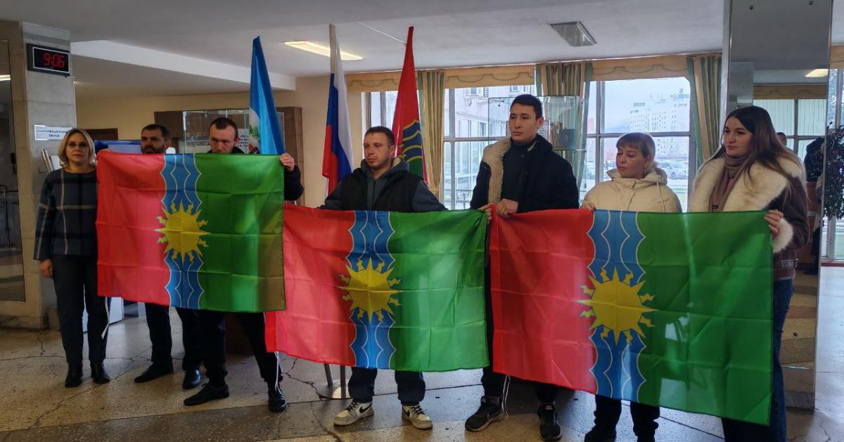 Группа людей держит флаги с символами.