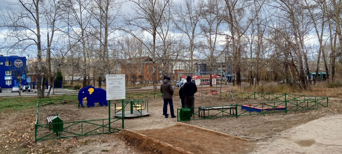 Детская площадка с людьми и синим зданием