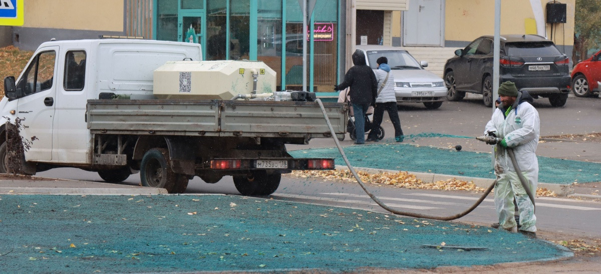 Трактор орошает газон на городском тротуаре
