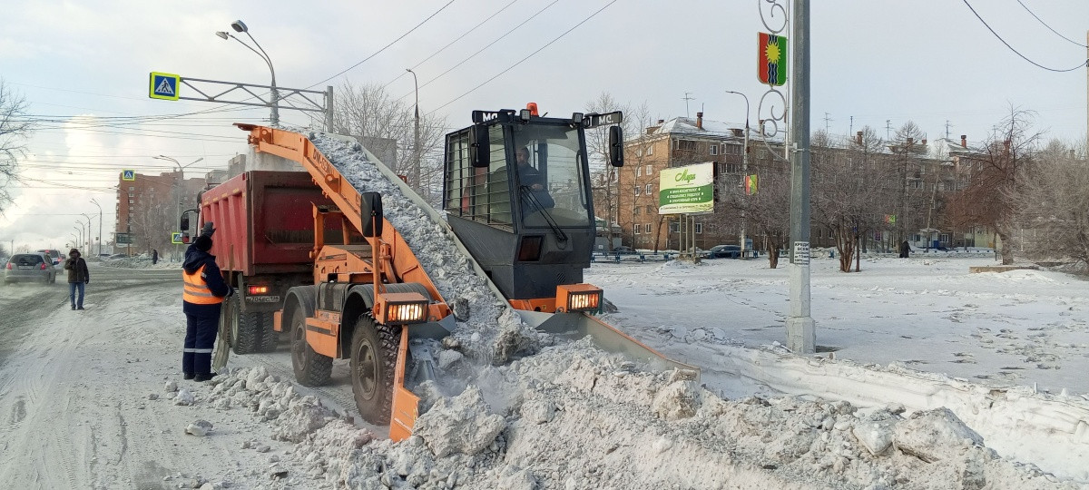 Уборка снега техникой на городских улицах зимой.