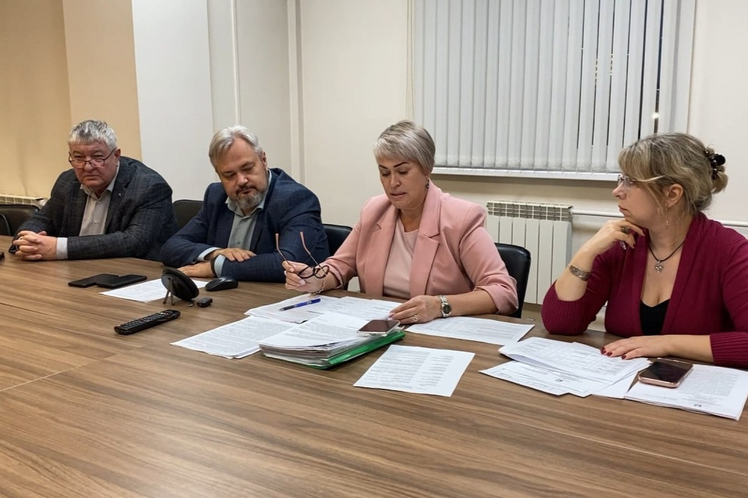 Участники заседания сидят за столом с документами.