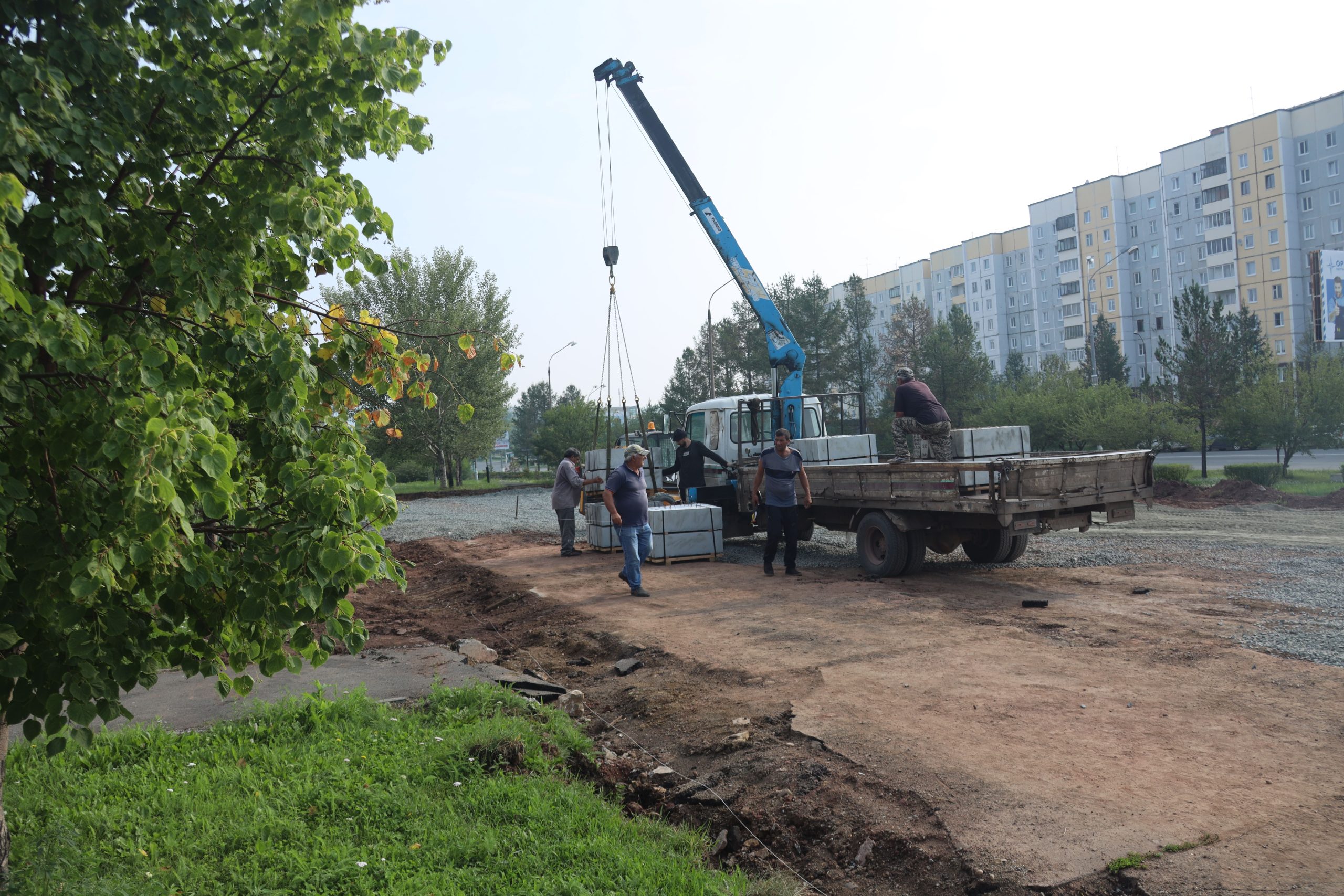 Рабочие укладывают тротуарную плитку на улице.