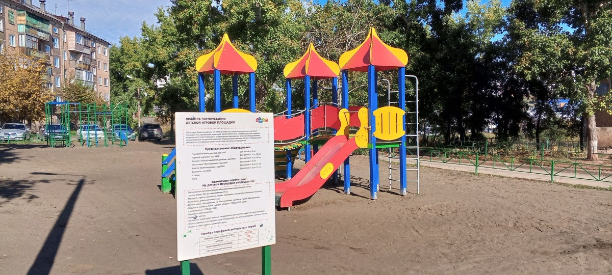 Цветная детская площадка с инструкцией на стенде.