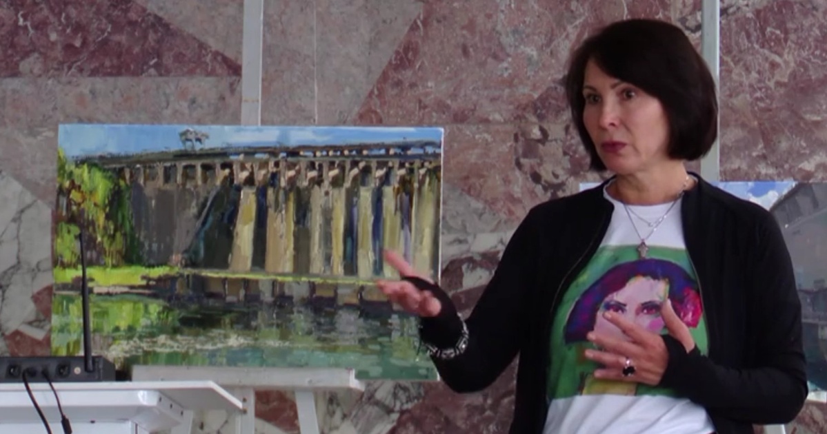 Женщина рассказывает о картине плотины на выставке.