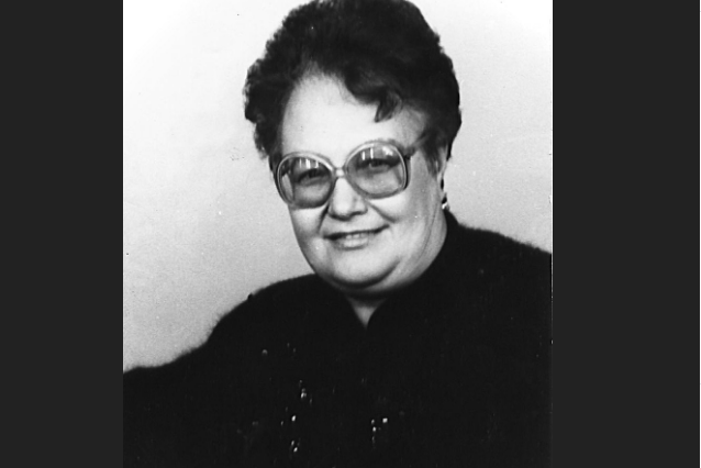 Пожилая женщина с короткими волосами в очках.