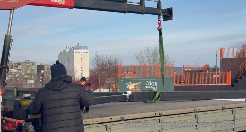 Рабочие и кран на грузовике зимой.