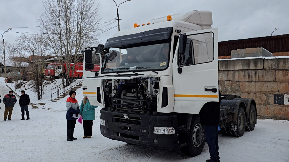 Грузовик на улице зимой, люди рядом.