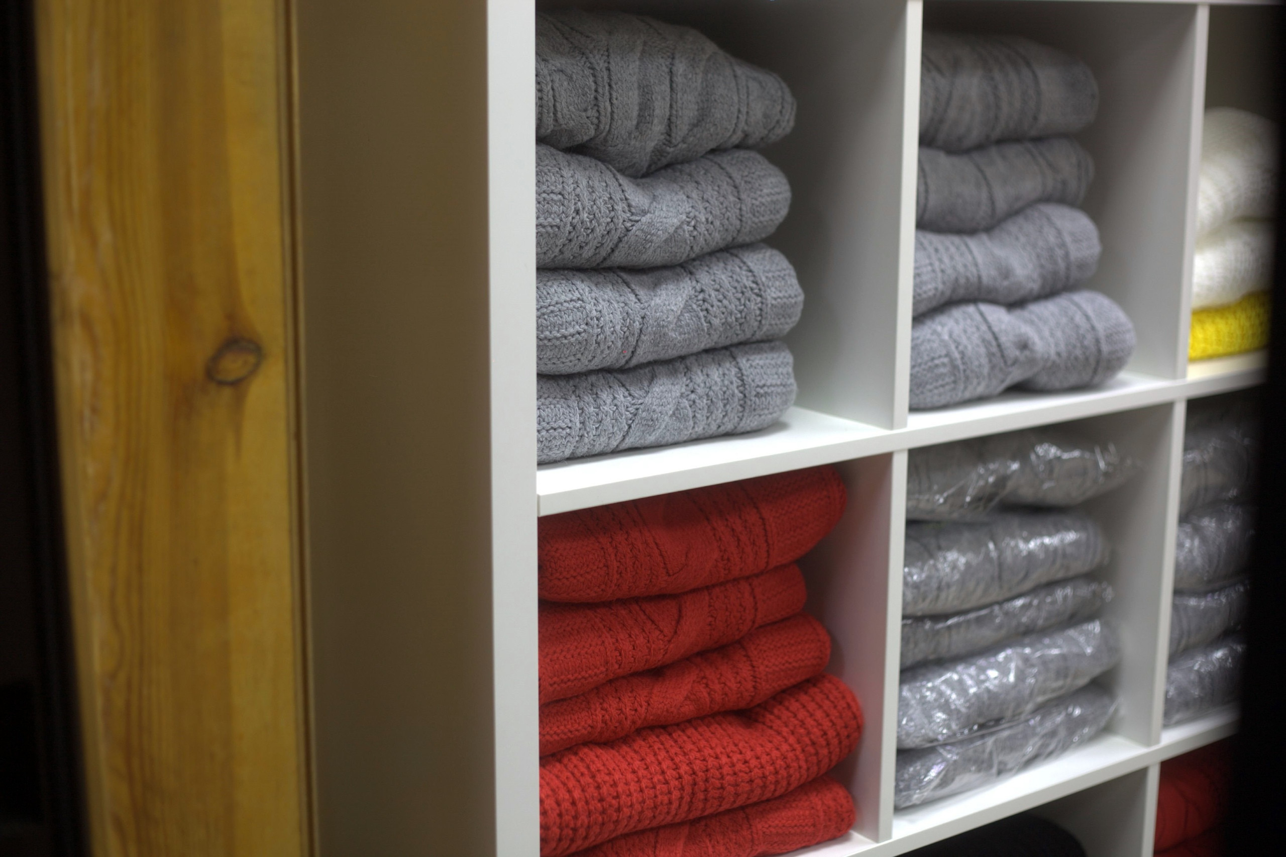 Полки с серыми и красными свитерами