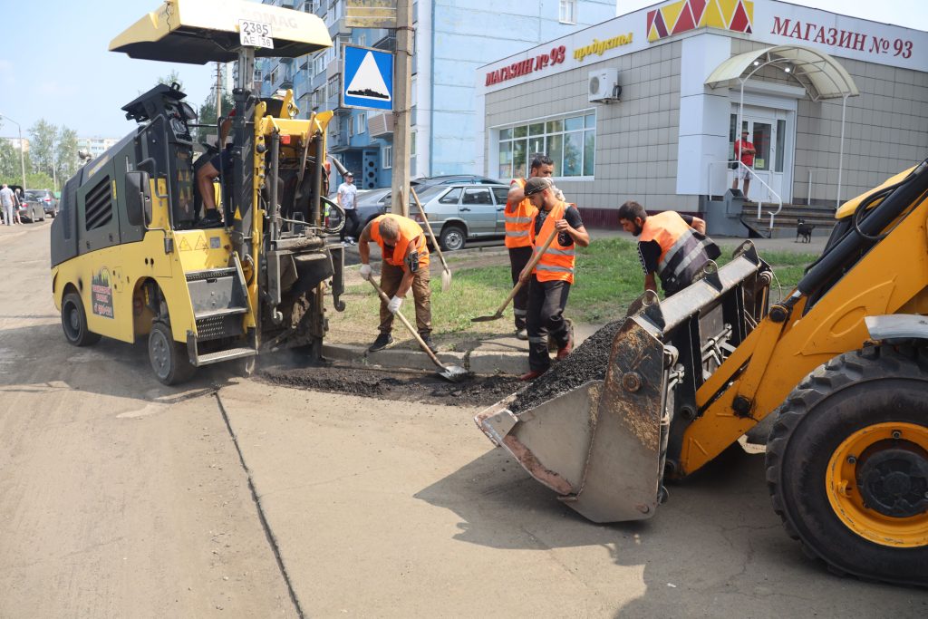 Дорожные рабочие укладывают асфальт перед магазином.