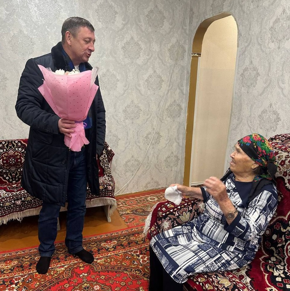 Мужчина вручает букет цветов женщине в комнате.