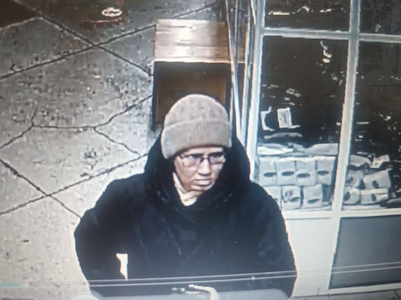 Человек в шапке и очках в магазине.