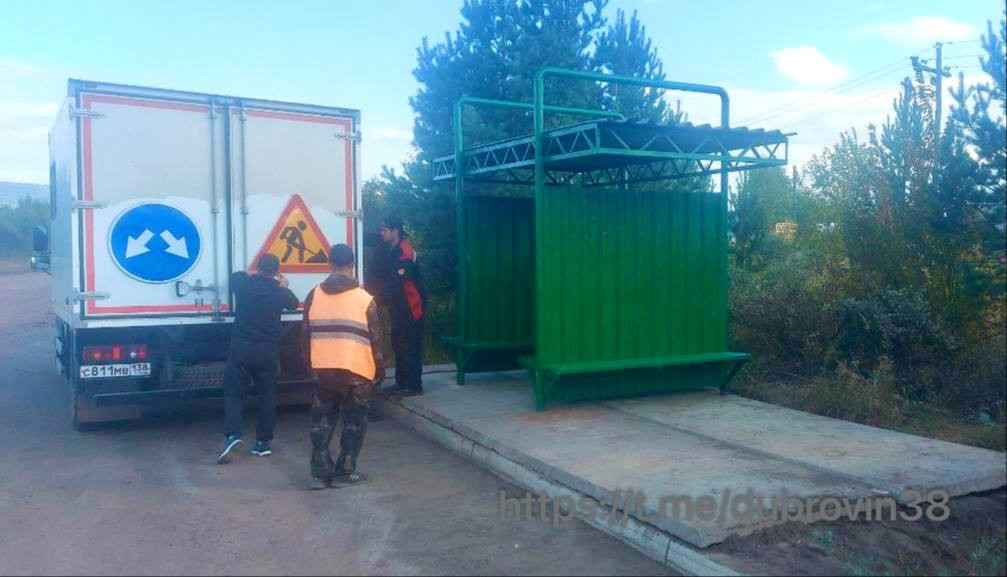 Грузовик и работники у остановки в лесу.