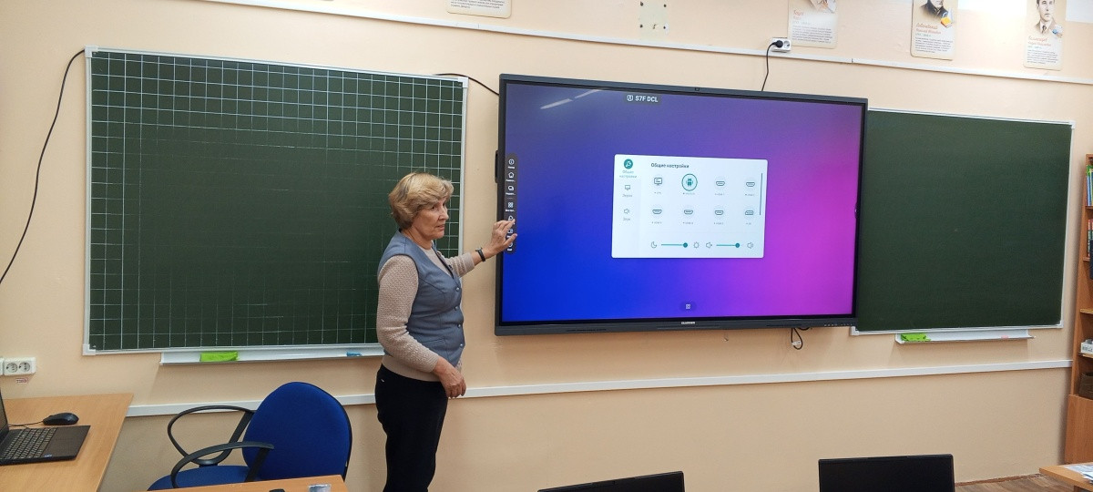 Учитель у интерактивной доски в классе.