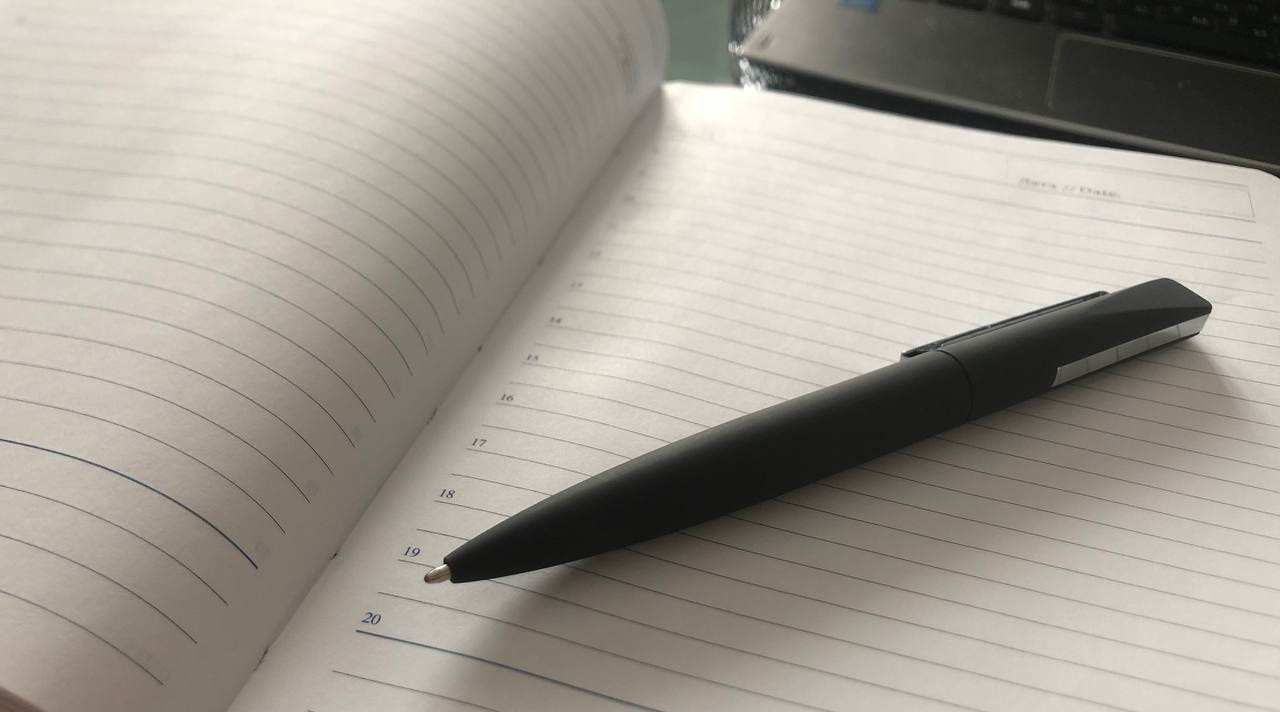 Ежедневник с ручкой на столе.
