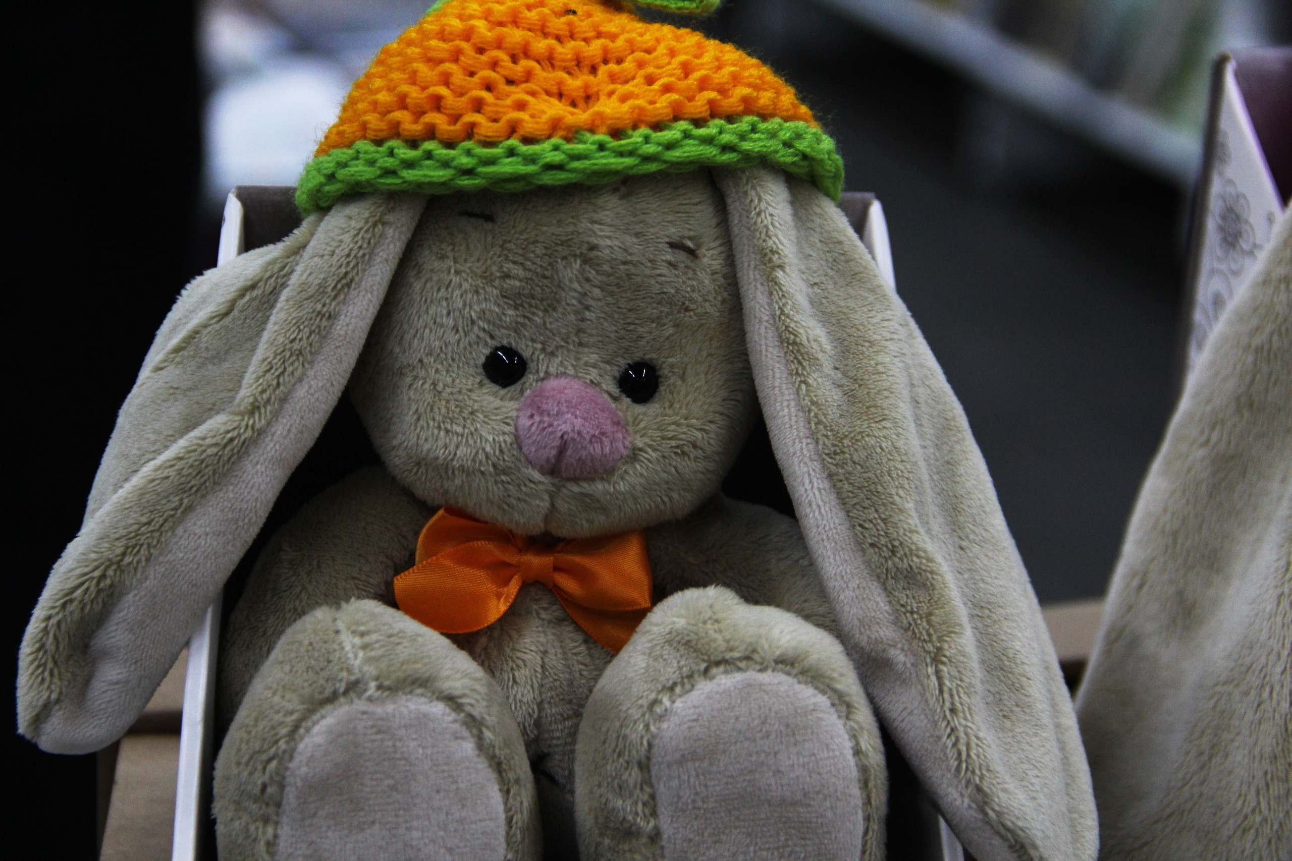 Плюшевый заяц в вязаной шапке и банте.