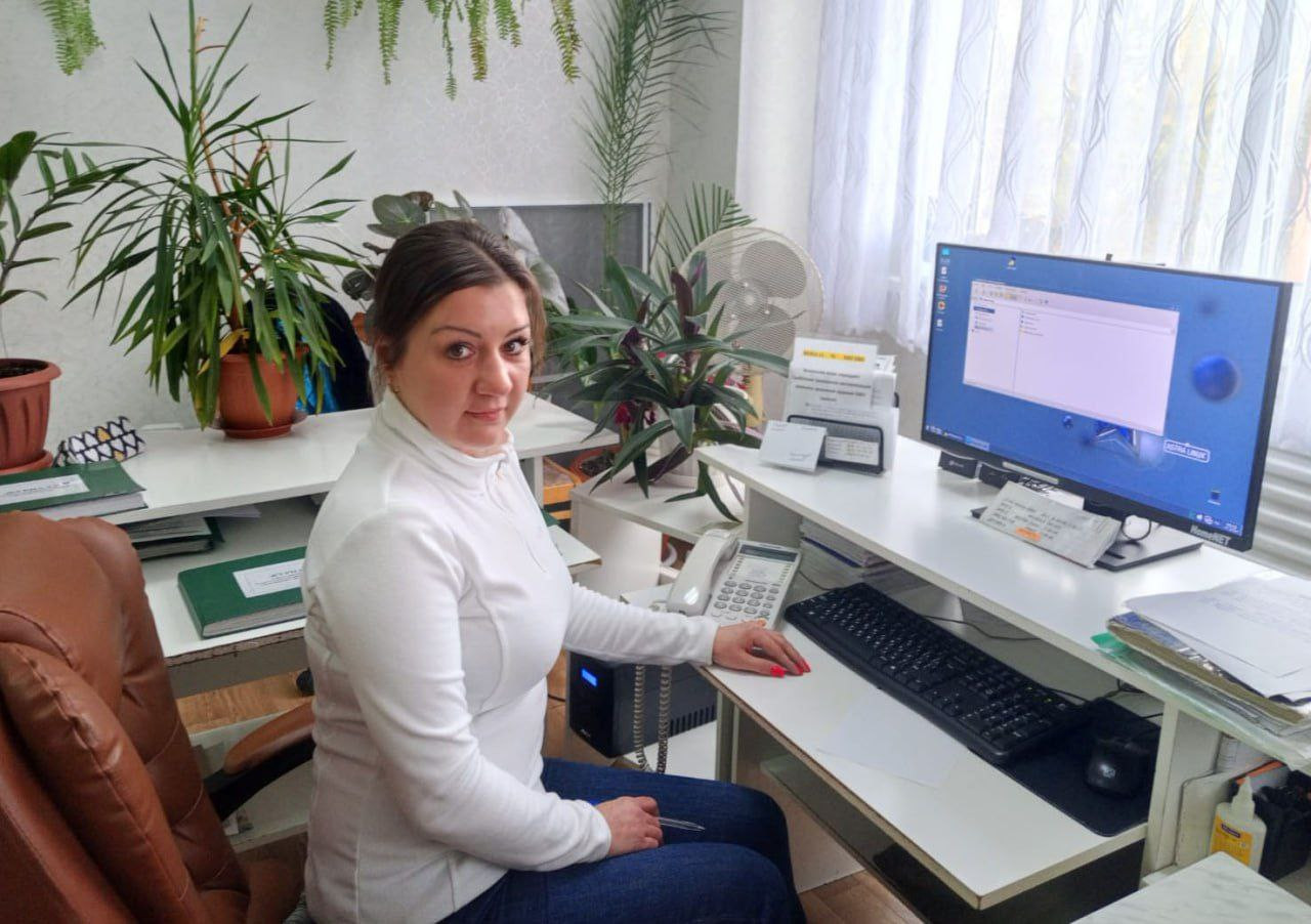 Женщина за компьютером в офисе с растениями.