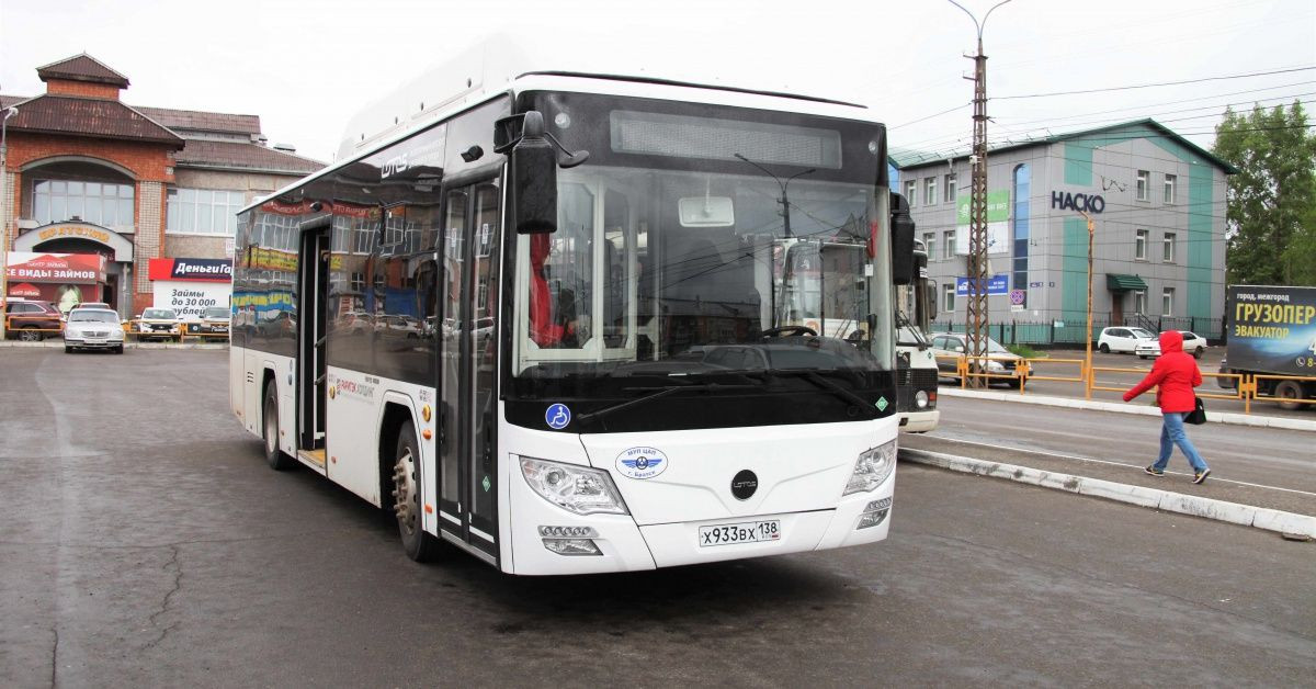 Городской автобус на улице, рядом проходят люди.