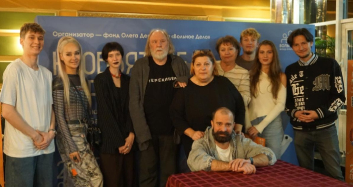 Группа людей на фоне баннера конференции.