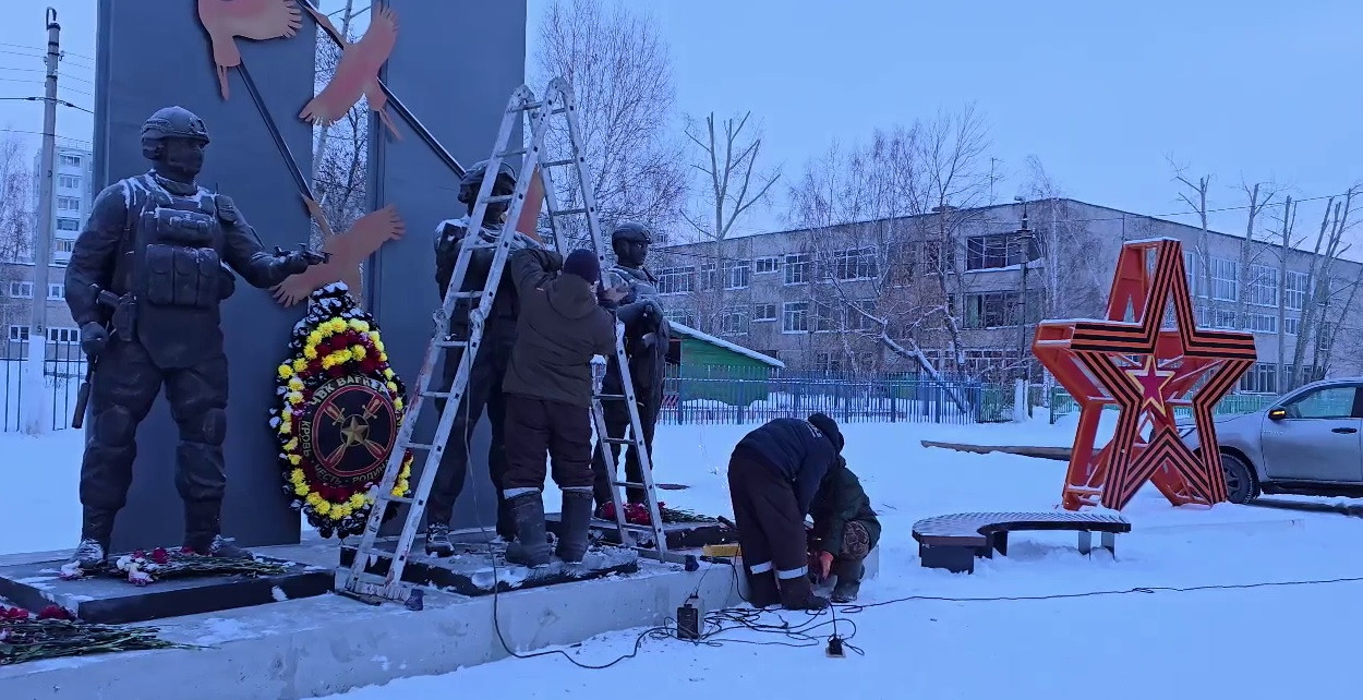 Монтаж памятника на улице зимой, с людьми и лестницей.