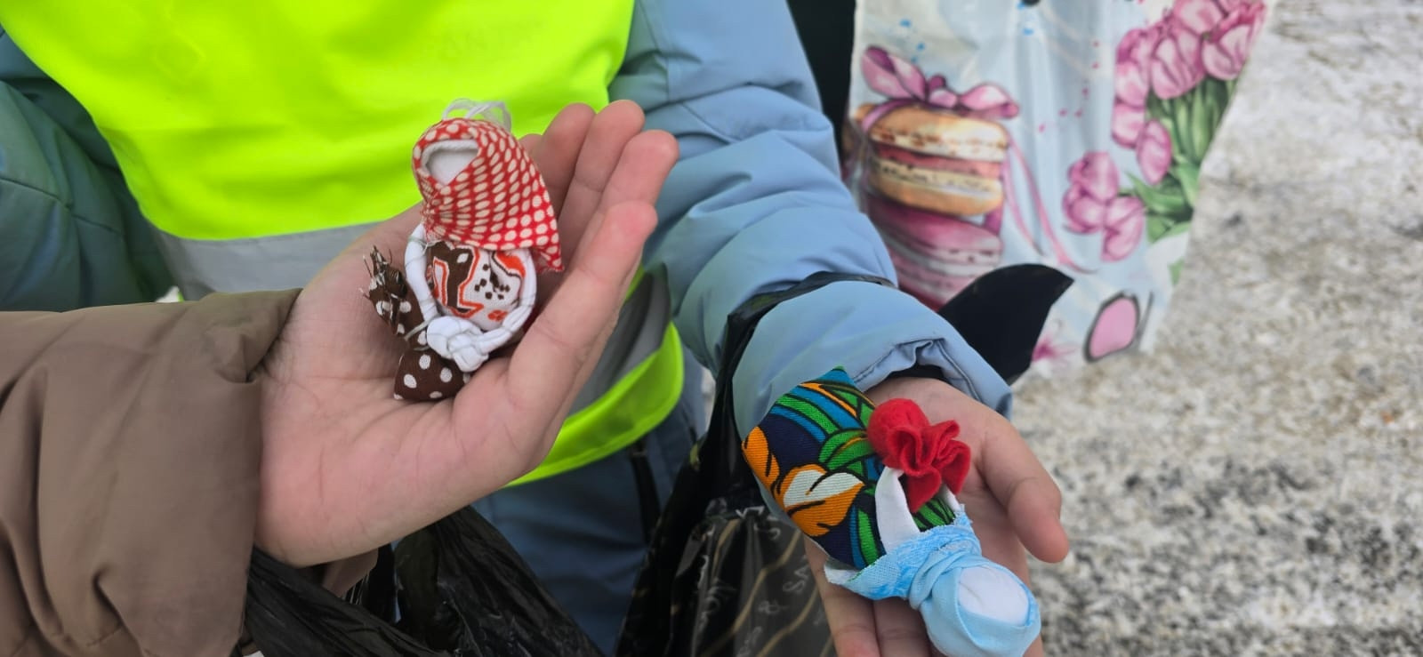 Руки держат кукол ручной работы из ткани.