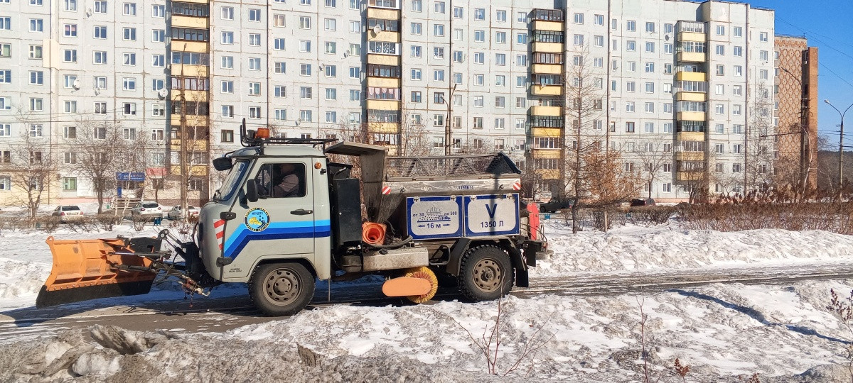 Коммунальная машина убирает снег возле здания