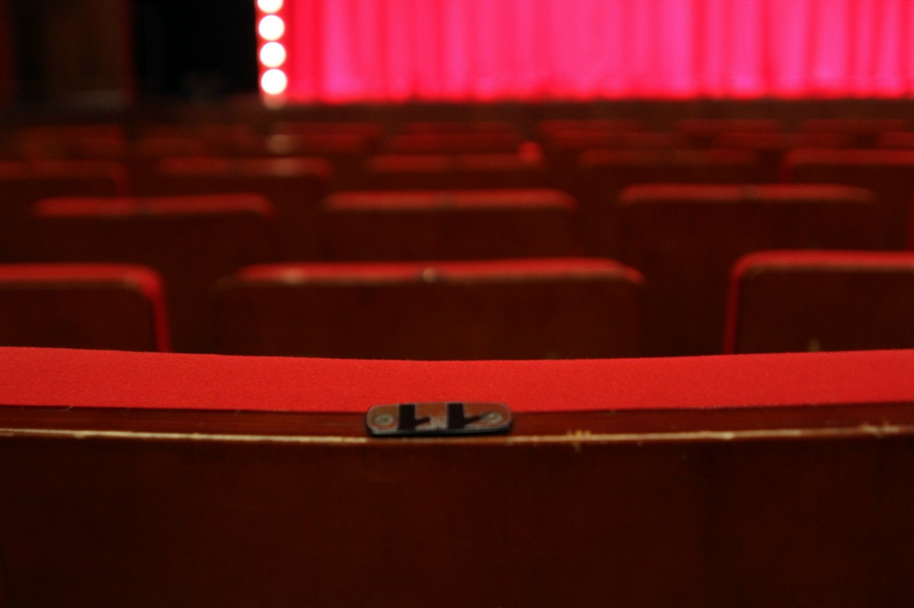 Пустой театр с красными креслами и занавесом.