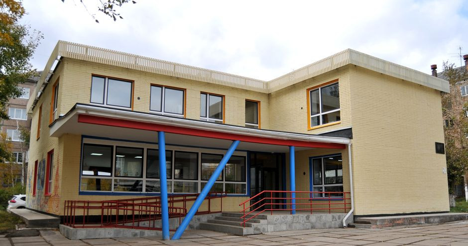 Жёлтое двухэтажное здание с красными перилами.