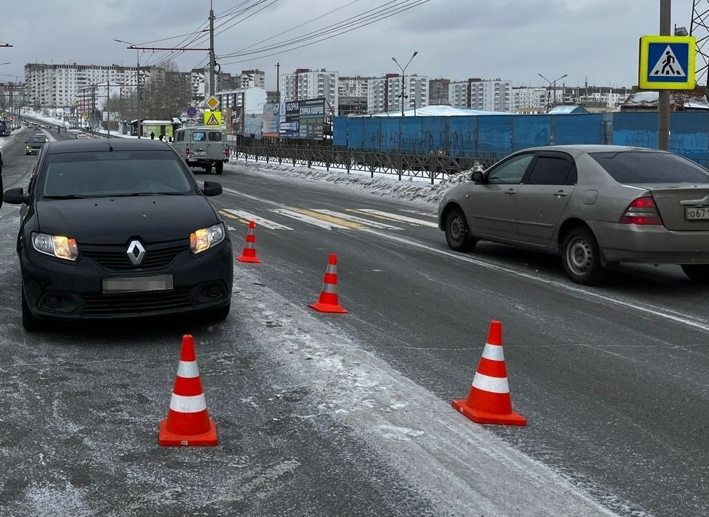 Машины на заснеженной дороге с оранжевыми конусами.