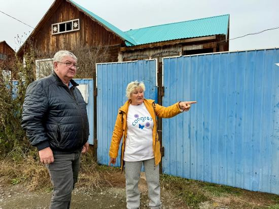 Взрослые обсуждают что-то у синего забора.