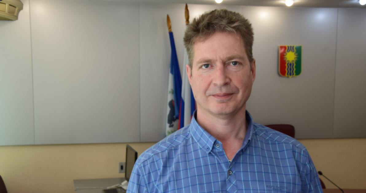 Мужчина в синей рубашке на фоне флагов