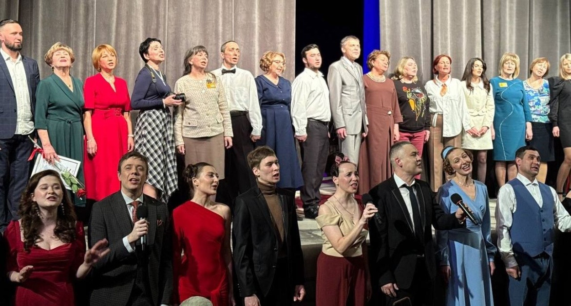 Группа людей поёт на сцене.