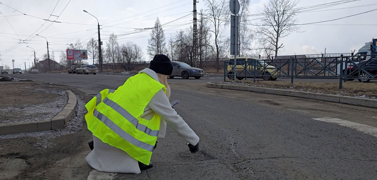 Человек в жилете проверяет покрытие дороги