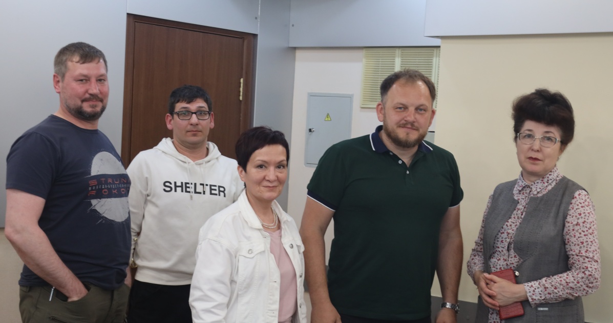 Группа людей стоит в помещении у двери.