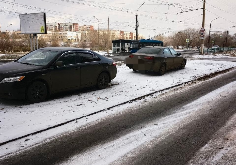 Автомобили припаркованы на заснеженной обочине дороги.