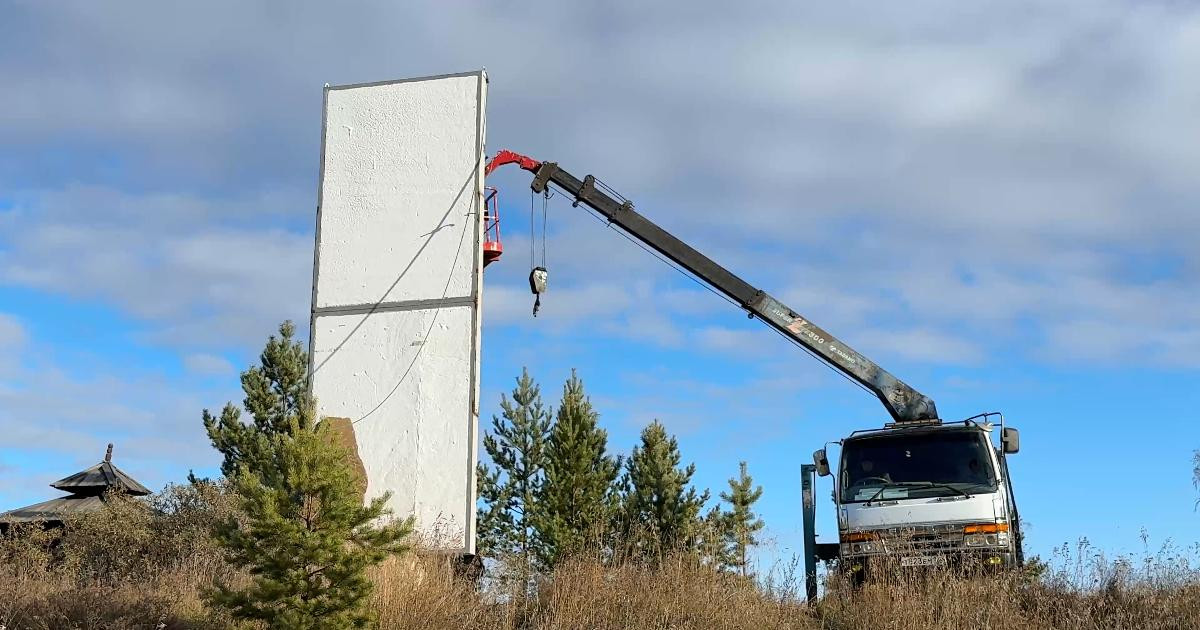 Кран поднимает человека на высотное здание.