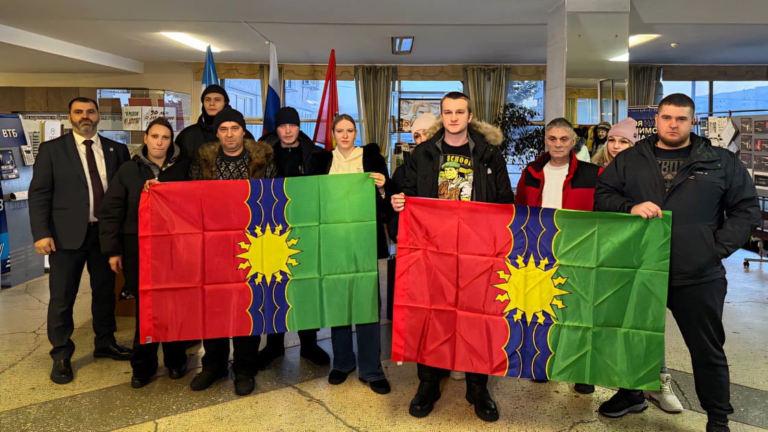 Люди с флагами на мероприятии в помещении.