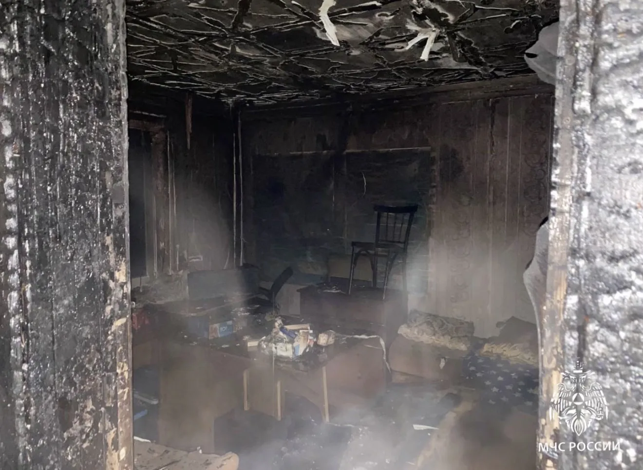 Задымлённая комната после пожара, обгоревшие стены.