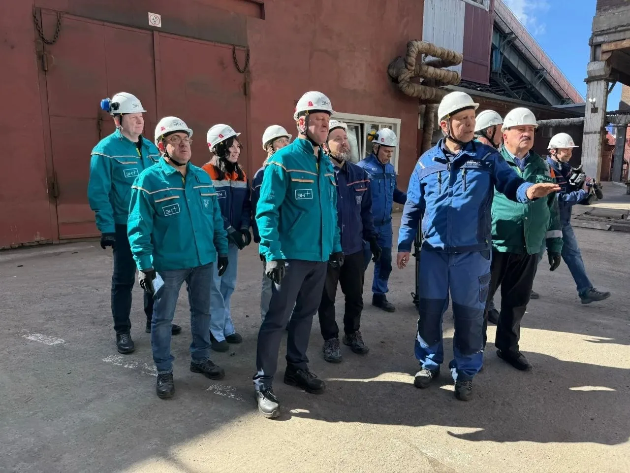 Группа людей в защитных касках на заводе