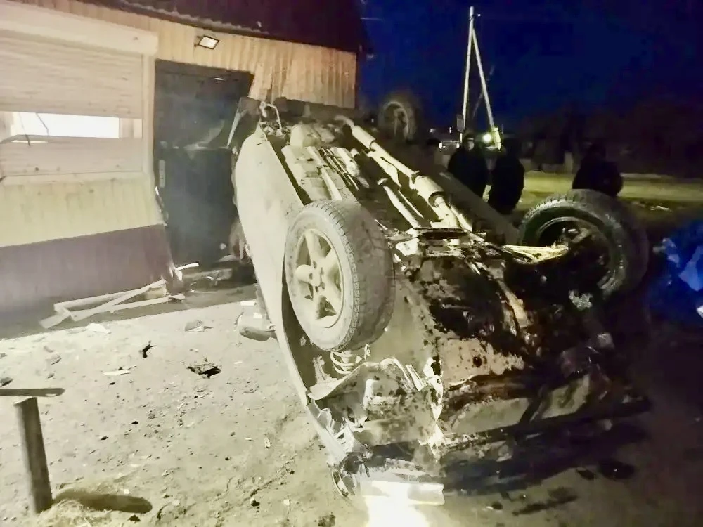 Перевернутый автомобиль после аварии у здания ночью
