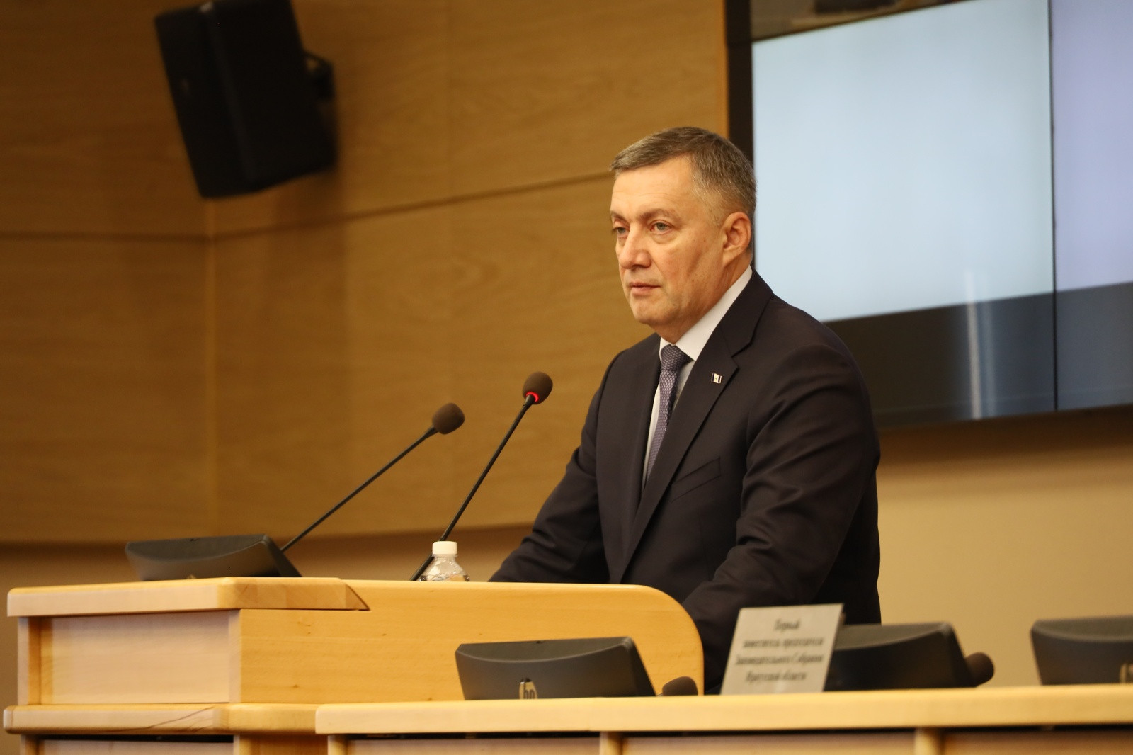 Мужчина в костюме выступает за трибуной