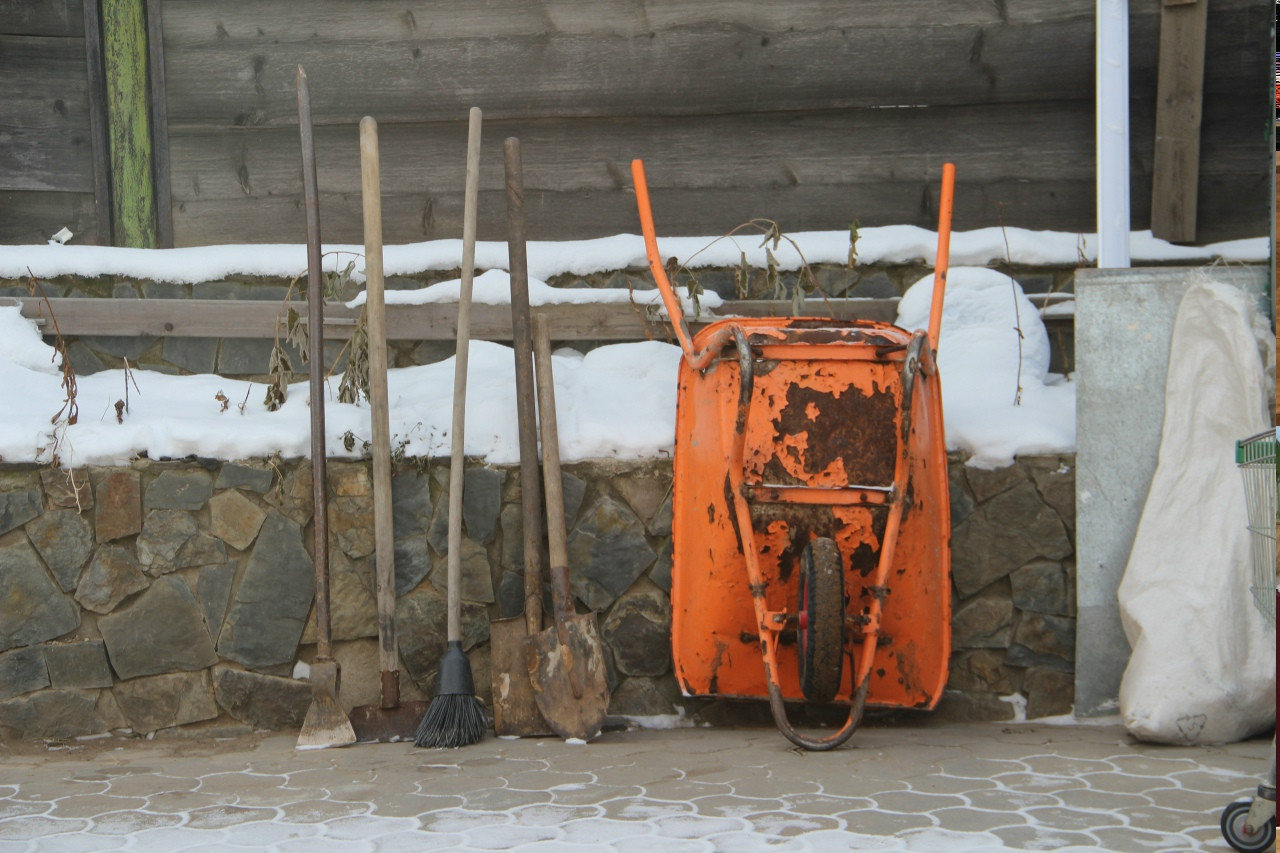 Садовые инструменты и оранжевая тачка зимой