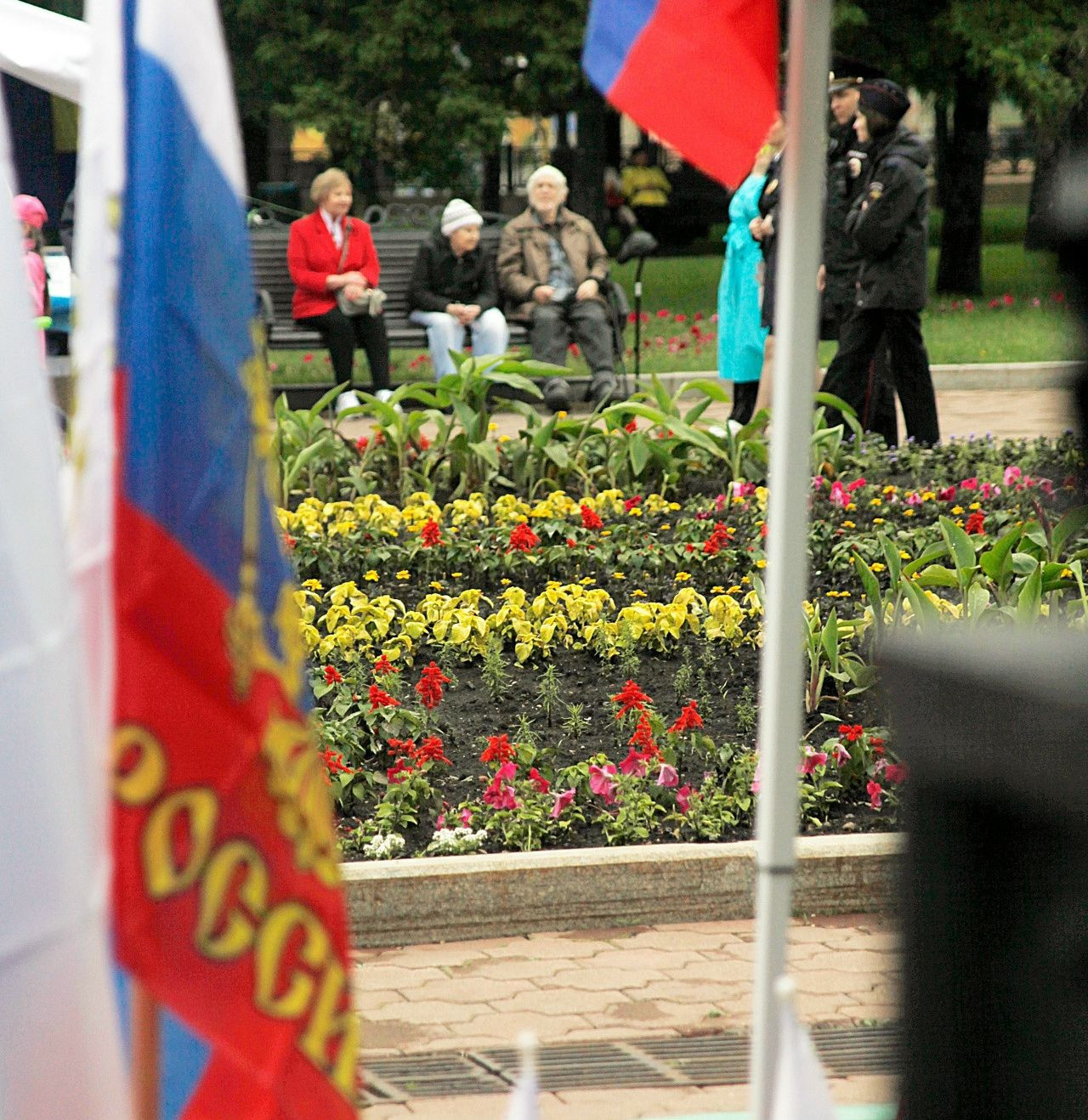 Цветочная клумба с российскими флагами на фоне.
