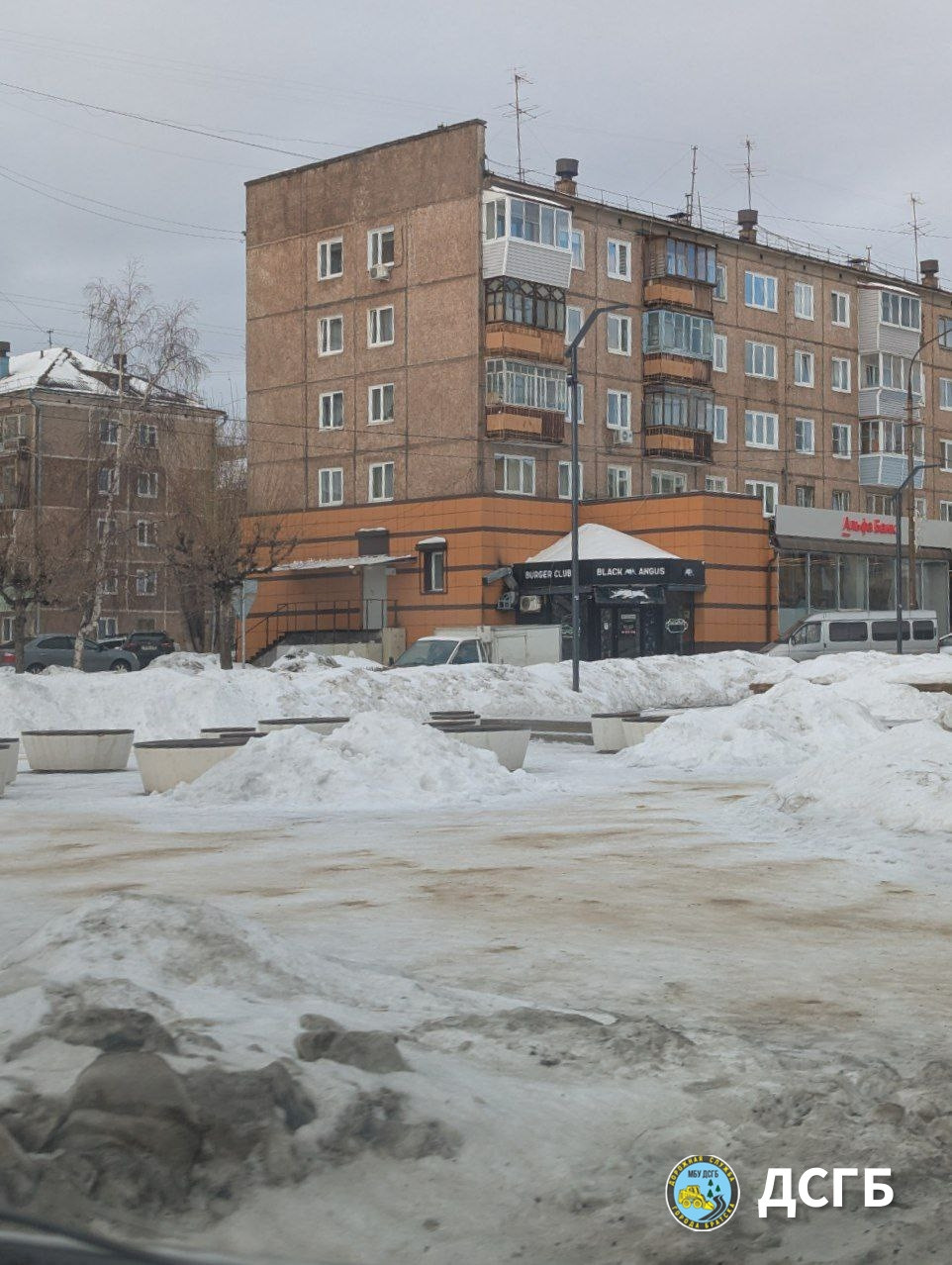 Заснеженная улица и жилой дом зимой