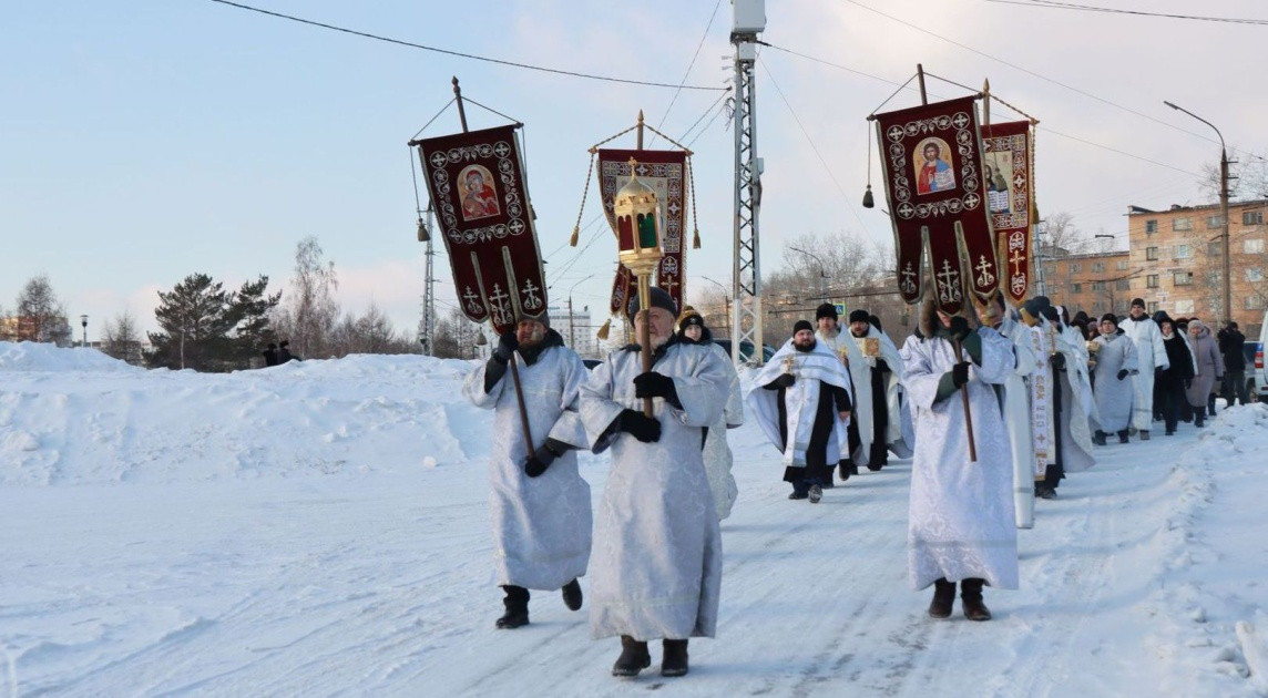 Религиозная процессия на снегу с иконами и хоругвями.