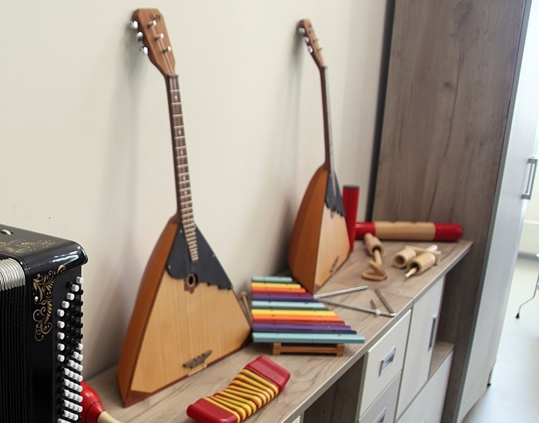 Русские инструменты: балалайки и аккордеон на шкафу.