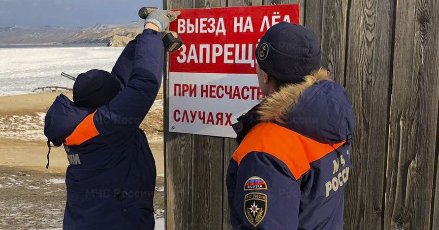 Двое мужчин укрепляют запрещающий знак во льду