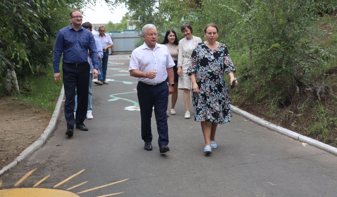 Группа людей идет по тротуару в парке.