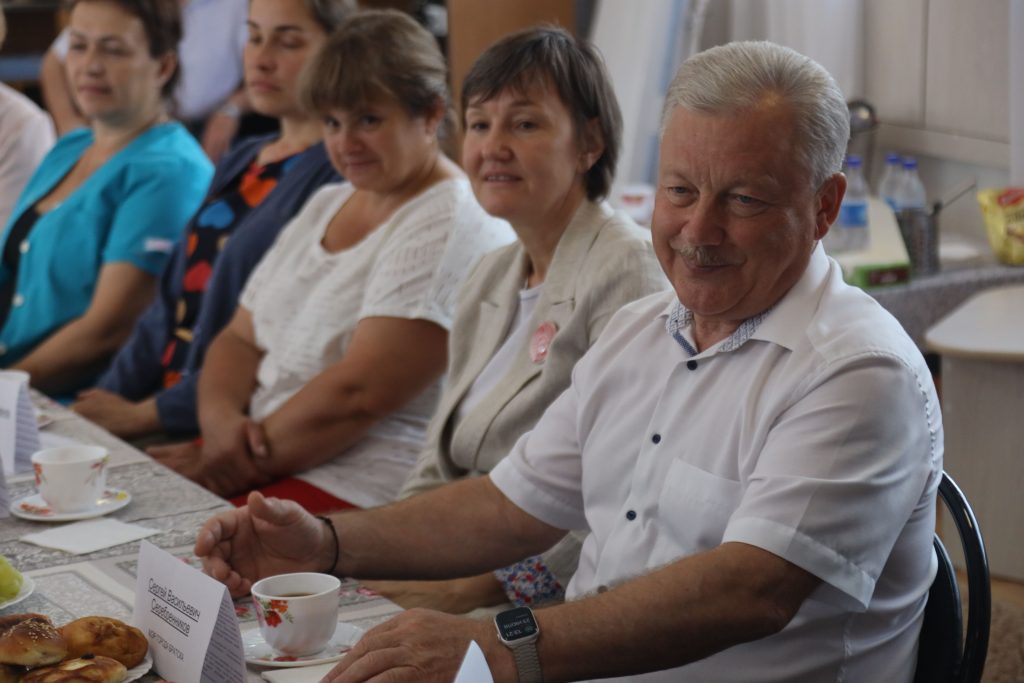 Группа людей на встрече за столом с чаем.