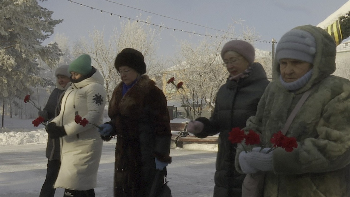 Группа женщин с гвоздиками зимой на улице.