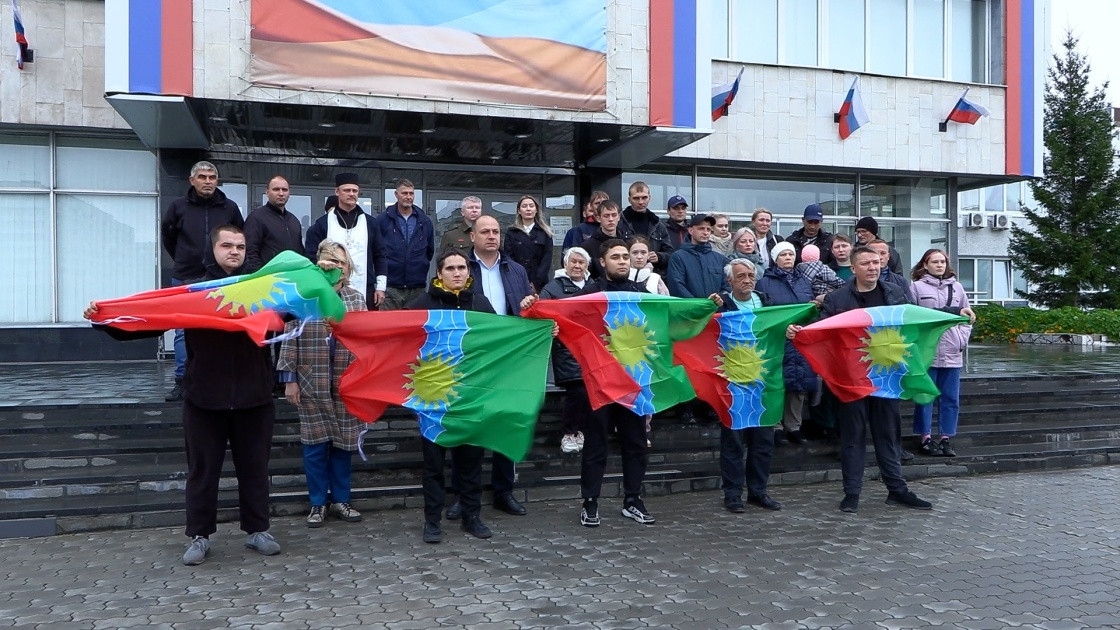 Группа людей с флагами перед зданием в России.